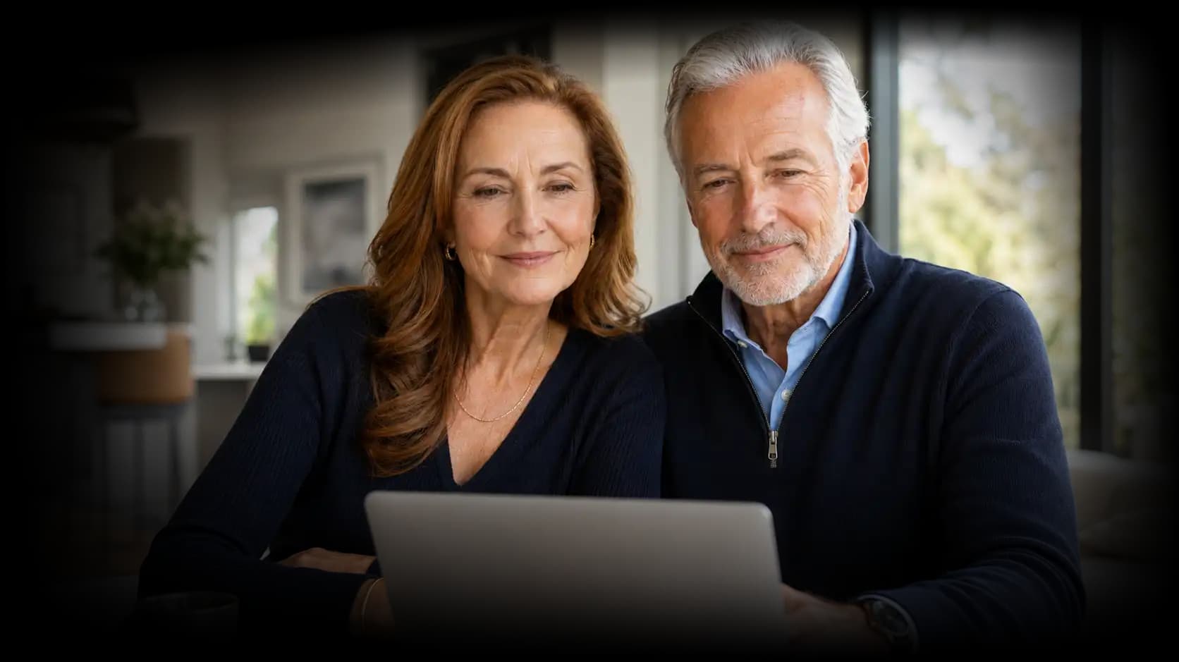 An older couple at home, reviewing their care plan together on a laptop